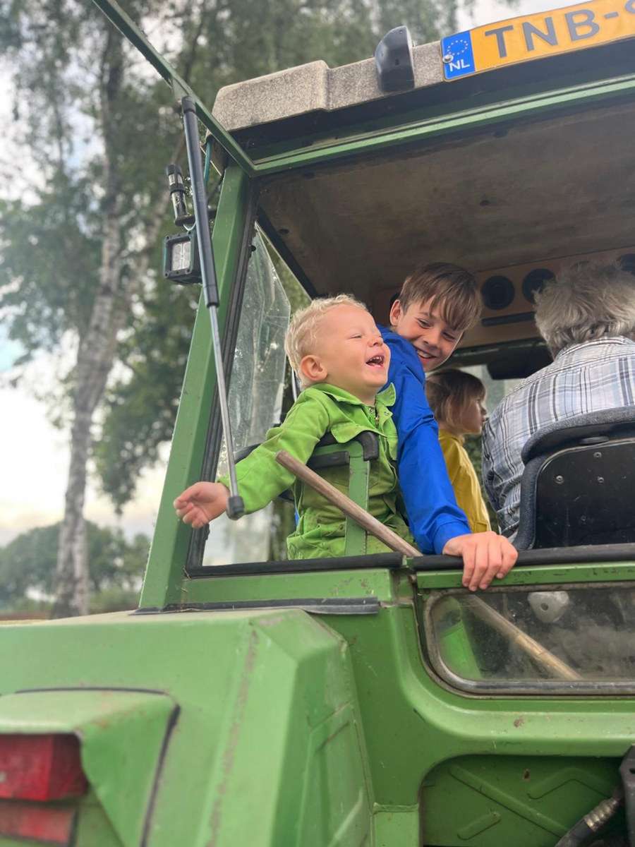 Twee lachende kinderen in de trekkercabine